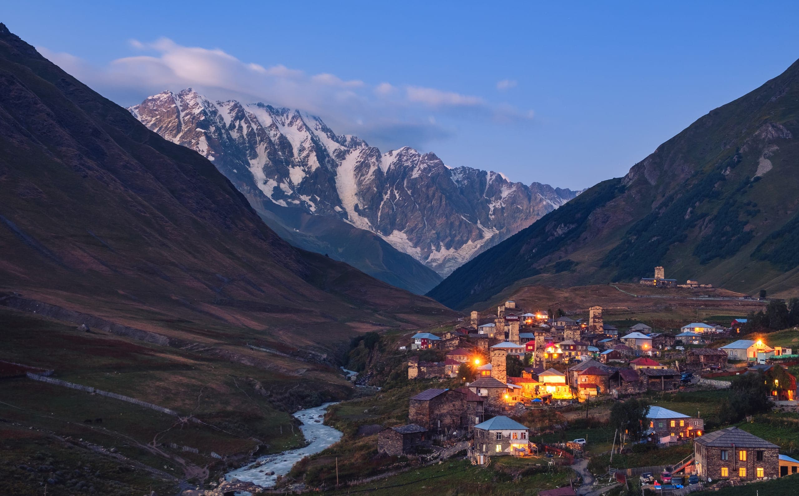 Ushguli village with medieval Svan towers at sunset in Upper Svaneti, Georgia, with the snow-capped peaks of the Greater Caucasus Mountains in the background