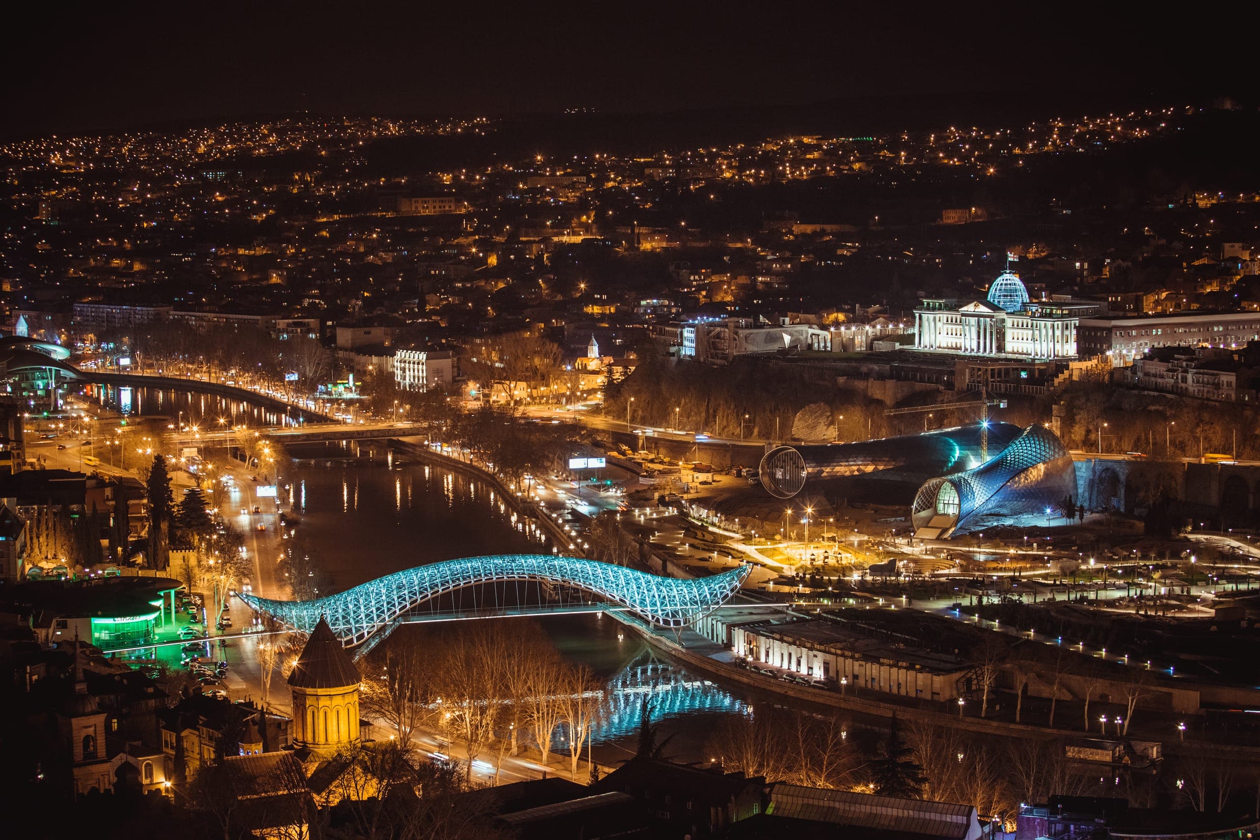 Night view of Tbilisi Old Town with illuminated historic buildings and the Narikala Fortress in the background